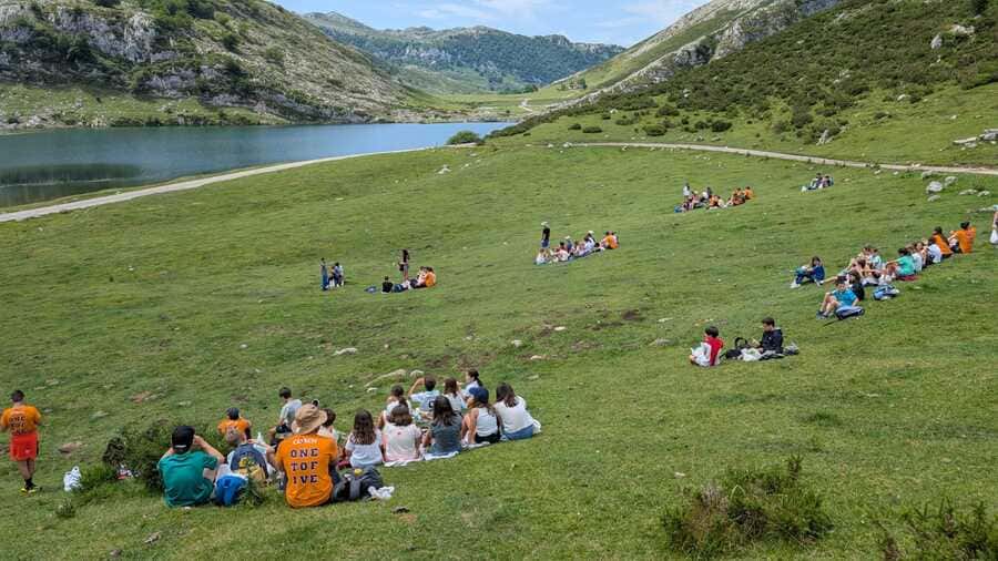 Jóvenes disfrutan frente a un lago en un campamento en inglés