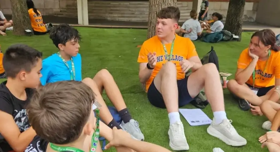 Groupe d’adolescents conversant avec un coach anglophone dans la colonie de vacances en anglais.