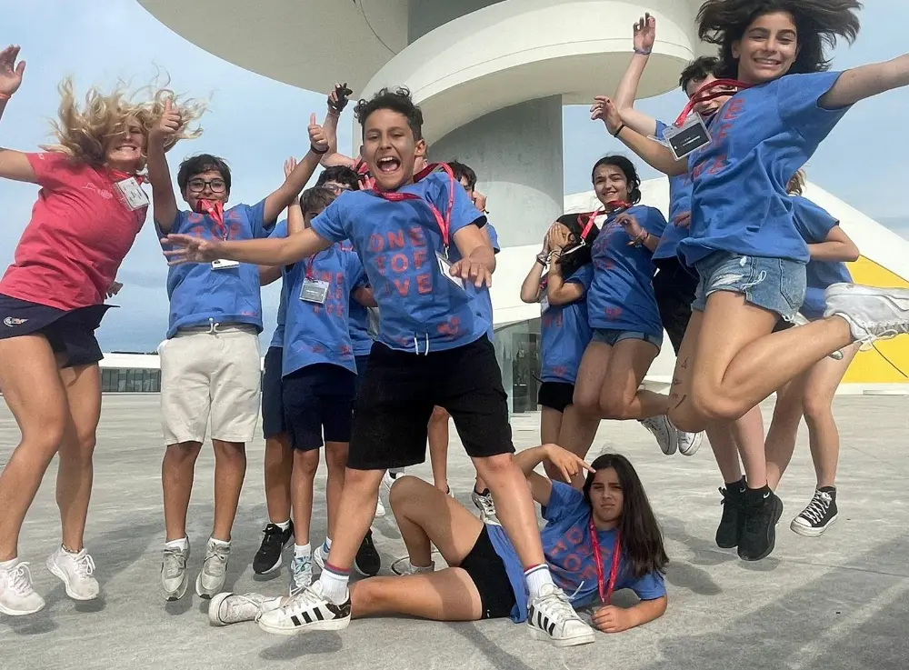 Coaches at the international camp jumping with participants at the Oscar Niemeyer Center.