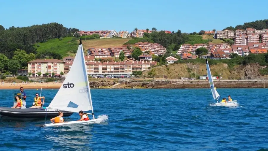 Junge Teilnehmer eines internationalen Sommercamps segeln auf dem Kantabrischen Meer