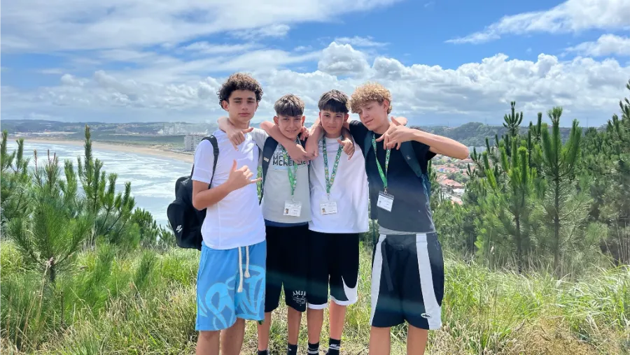 Jeunes participants en randonnée posant devant une plage asturienne au camp d'été anglais the Village
