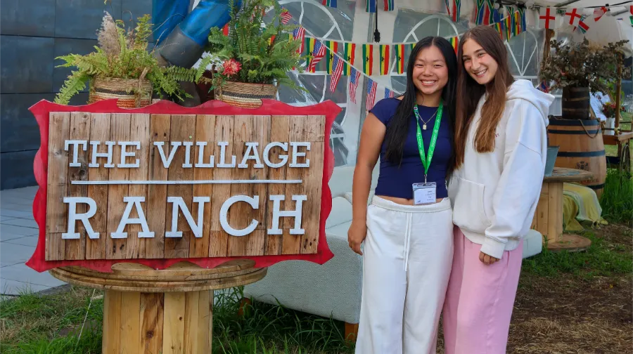 Zwei Mädchen vom internationalen Camp the Village vor dem Hoteleingangsschild