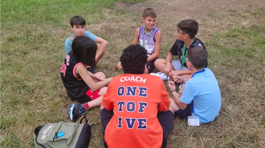 Gruppe von Kindern mit ihrem internationalen Coach in einer One-to-Five-Session im internationalen Camp The Village