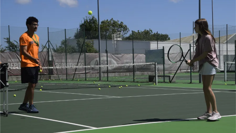 Un coach international explique à une participante lors de l'activité tennis au camp The Village