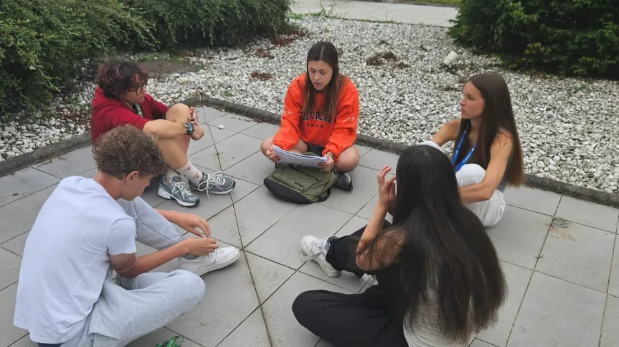 Group of teenagers speaking English with their international coach at The Village camp