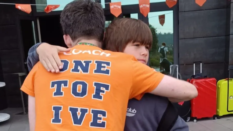 Un coach da la bienvenida a un joven participante en el campamento de verano the Village