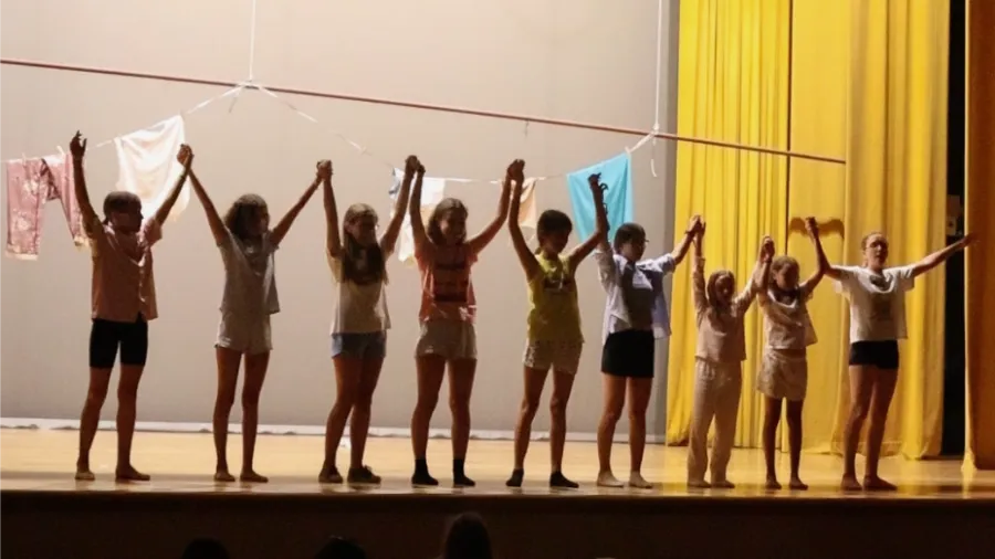 Grupo de chicas ensayan la actividad de danza en el salón de actos del campamento the Village