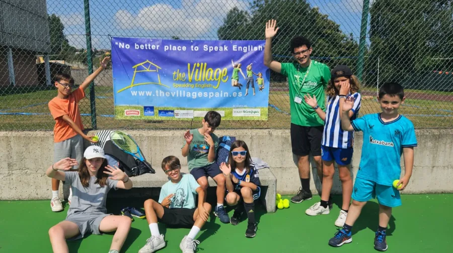 Sept jeunes joueurs de tennis avec leur coach au camp d’été The Village
