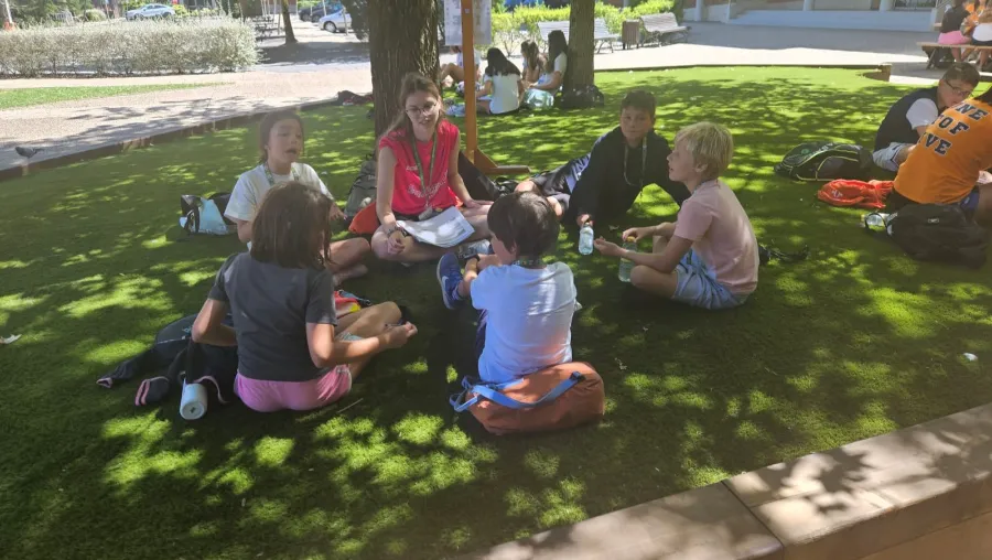 A group of five boys talk in English with their international coach at the Village camp