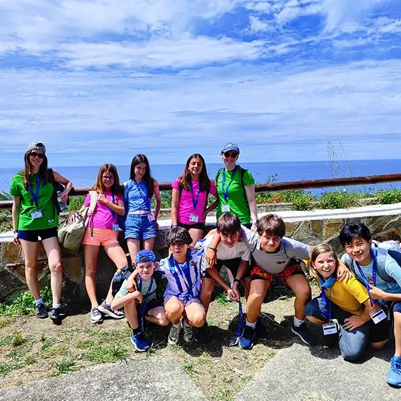 Eine Gruppe Jugendlicher mit einem internationalen Coach auf einem Waldpfad in Asturien