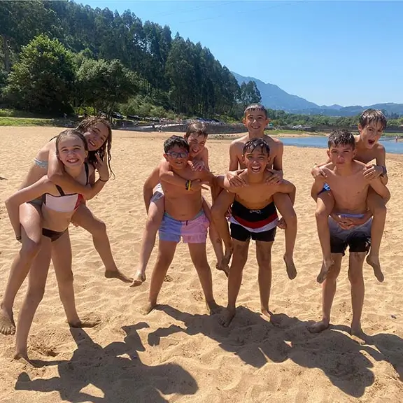 Acht Kinder haben Spaß am Strand während des internationalen Sommerlagers in Spanien