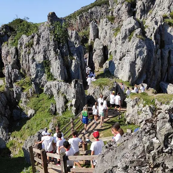 Eine Gruppe von Kindern wandert auf einem Pfad zwischen imposanten Felsen im internationalen Sommerlager in Spanien