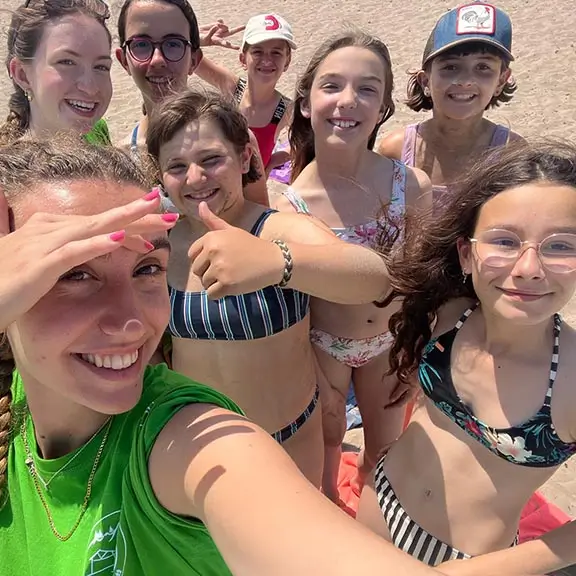 Mädchen des Sommerlagers in Spanien mit ihrem internationalen Coach an einem Strand in Asturien