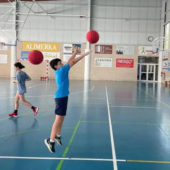 Kind wirft den Ball in der Basketballaktivität im Sommerlager in Spanien