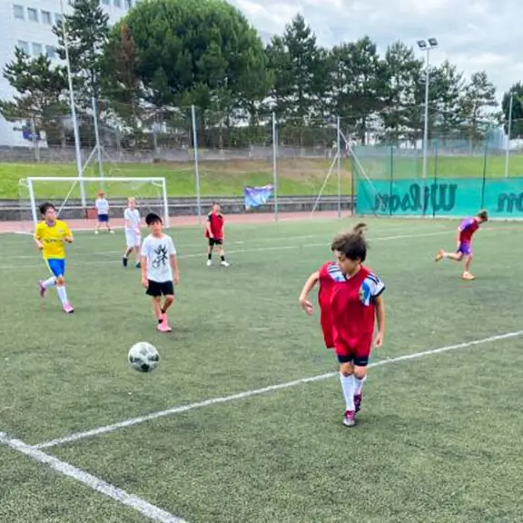 Kinder spielen Fußball mit internationalen Trainern im Sommerlager