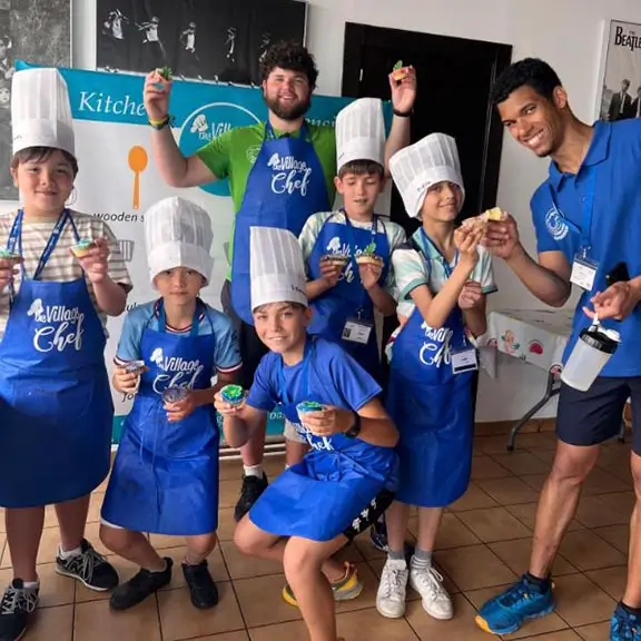 Gruppe von Kindern zeigt ihre Kreationen in der Kochaktivität mit englischsprachigen Trainern