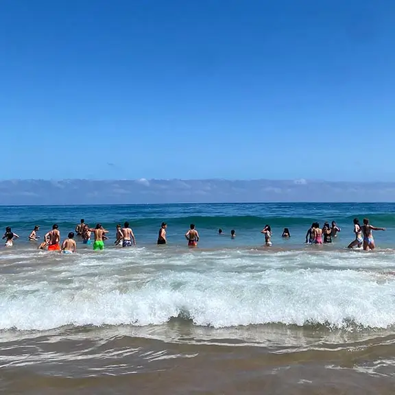 Jugendliche aus dem internationalen Sommerlager baden am Strand von Salinas