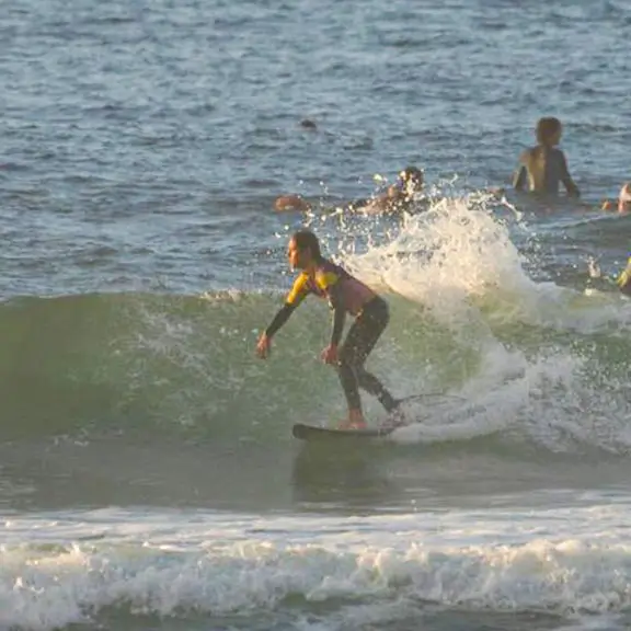 Teilnehmer genießt das Surfen am Strand von Salinas im Sommerlager