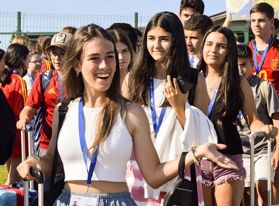 Eine Gruppe von Jugendlichen wird von ihren neuen Freunden bei ihrer Ankunft im englischen Camp the Village begrüßt