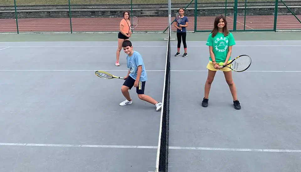 Kinder posieren auf einem der Außentennisplätze des Sommercamps für Kinder in Spanien