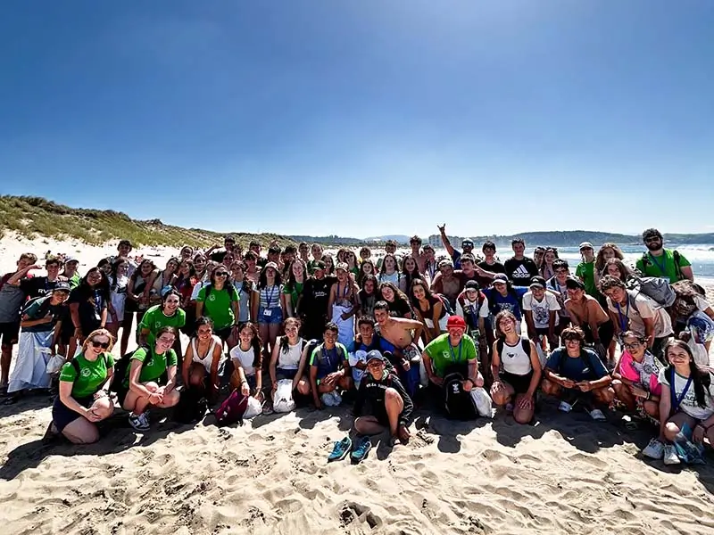 Gruppe von Jugendlichen genießt Aktivitäten am Strand von Salinas, Asturien, während des Sommerlagers in Spanien