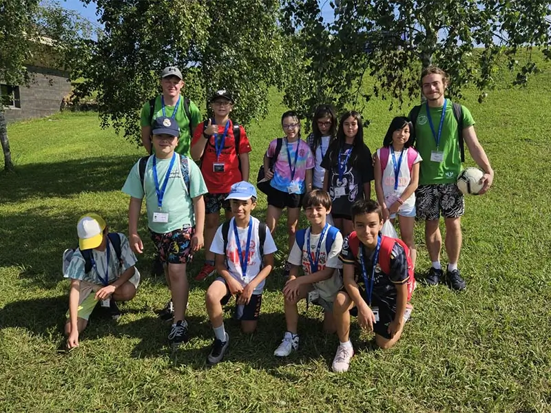 Eine Gruppe von Jungen in den Gärten des Englischlagers the Village mit ihrem internationalen Coach