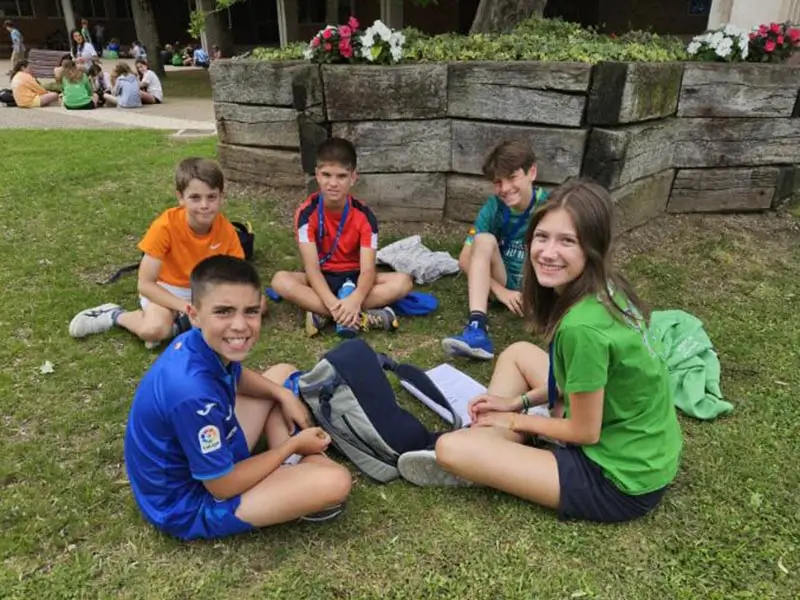 Vier Kinder sprechen mit ihrem internationalen Coach in einer Eins-zu-Fünf-Session im Englischlager the Village