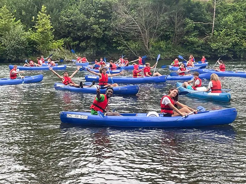 Teilnehmer des Englisch Sommercamp in Spanien paddeln einen Fluss in Asturien im Kajak hinunter