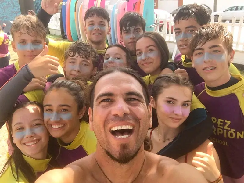 Internationaler Coach der Surfing-Aktivität im Englisch Sommercamp in Spanien mit einer Gruppe Teilnehmer