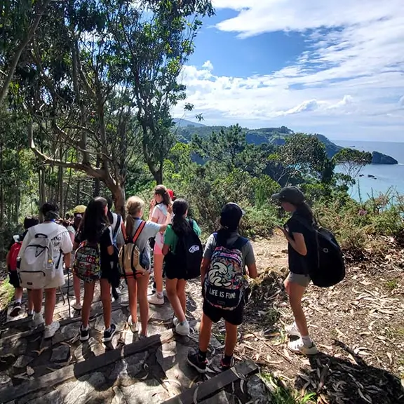 A group of kids with backpacks enjoying the Asturian coast during an excursion