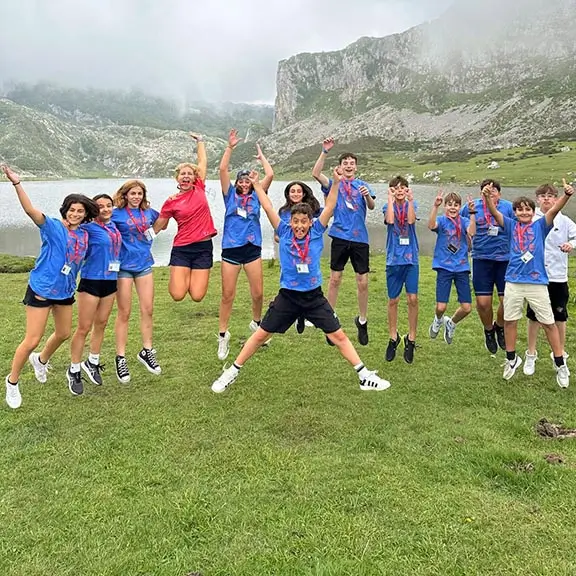 Group jumping in front of a mountain lake during a summer camp excursion