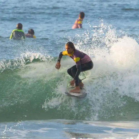 Participant surfing a wave at Salinas beach during the summer camp