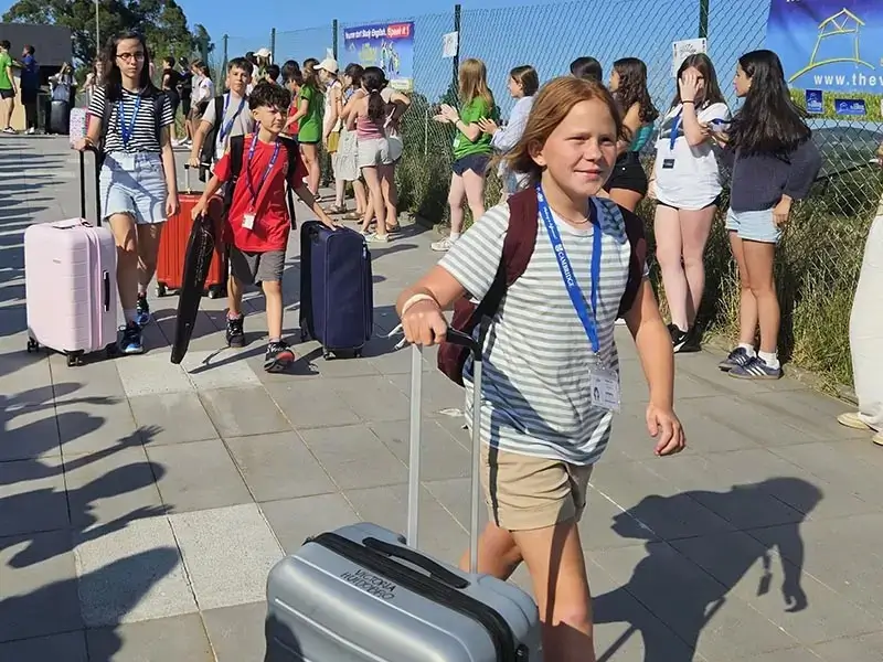 A group of children is welcomed by their peers upon arrival at the English Camp