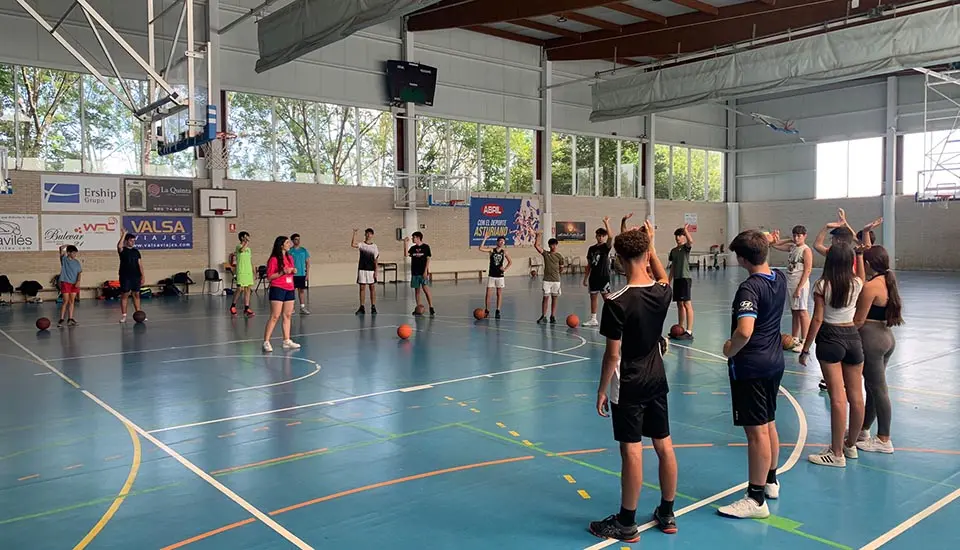 Group of young participants warming up for basketball with international coaches at the summer camp in Spain