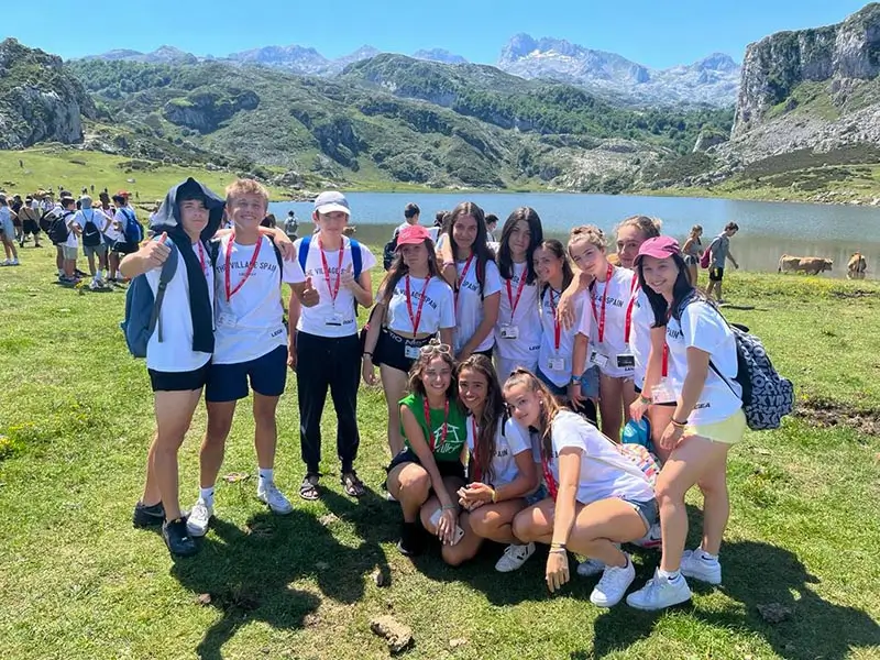 Group of teenagers aged 13 to 17 in front of a lake during a mountain excursion organized by the summer camp in Spain for teens