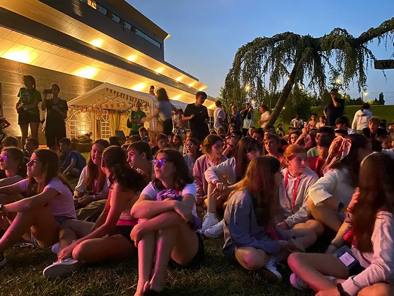 Young people participating in a show at nightfall at the English camp the Village