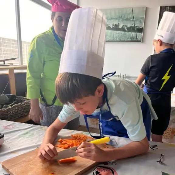 Chico cocinando en la actividad de cocina en inglés del campamento de inglés