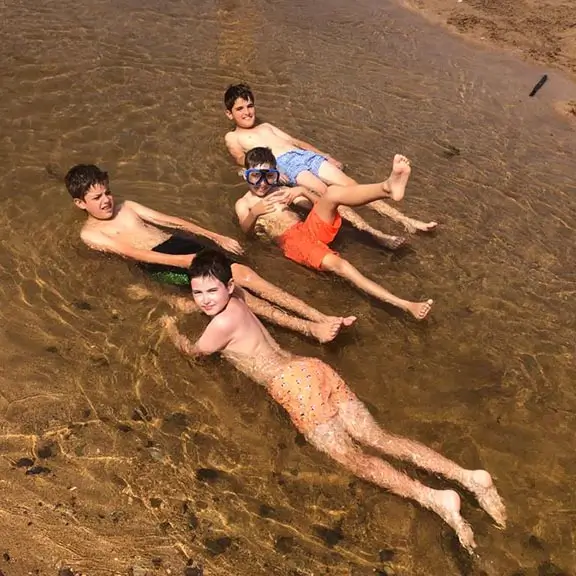 Cuatro niños bañándose en la orilla de la playa en el campamento