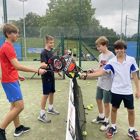 Participantes del campamento inglés en España se saludan tras un partido de pádel