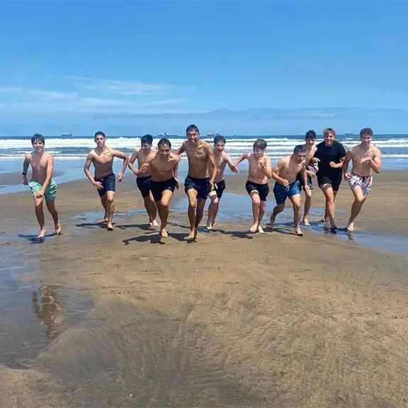 Jóvenes corriendo en una playa del norte de España en el campamento internacional