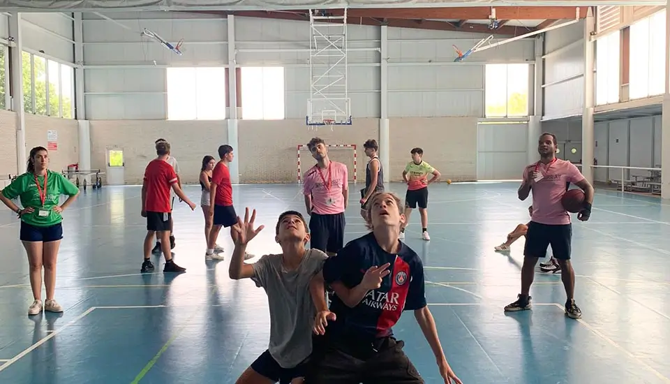 Chicos entrenando a baloncesto con sus coaches internacionales en el campamento inglés en España