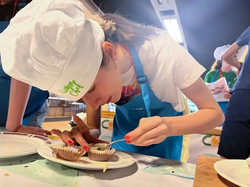 Joven en el campamento inglés finalizando una receta durante la actividad de cocina