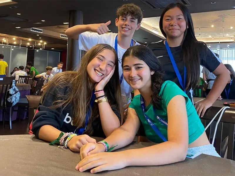 Cuatro jóvenes participantes en el campamento inglés en España the Village posan sonrientes en el comedor