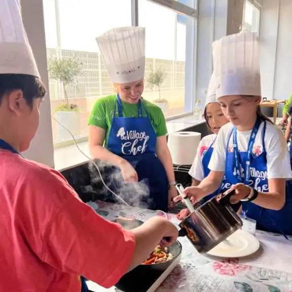 Enfants cuisinant sous la direction d'un entraîneur international dans la colonie de vacances internationale the Village