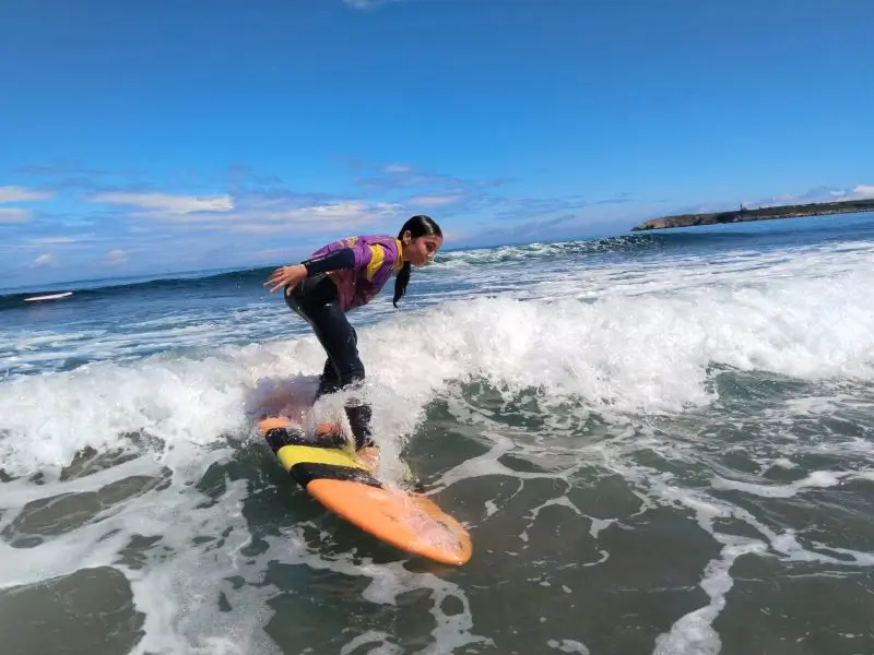 Une jeune fille lors de l’activité surf sur la plage de Salinas pendant la colonie de vacances internationale en Espagne