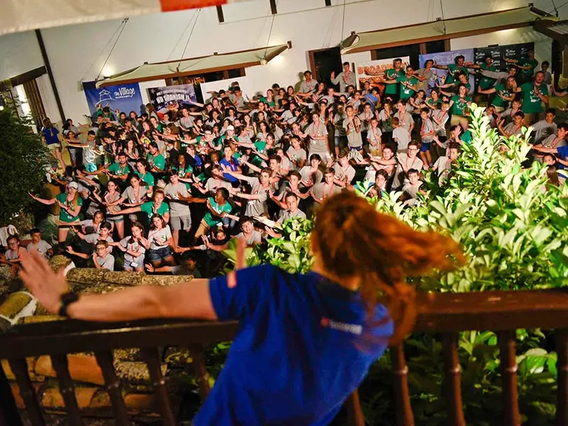 Une coach américaine dirigeant une activité de danse avec de nombreux participants à la colonie internationale