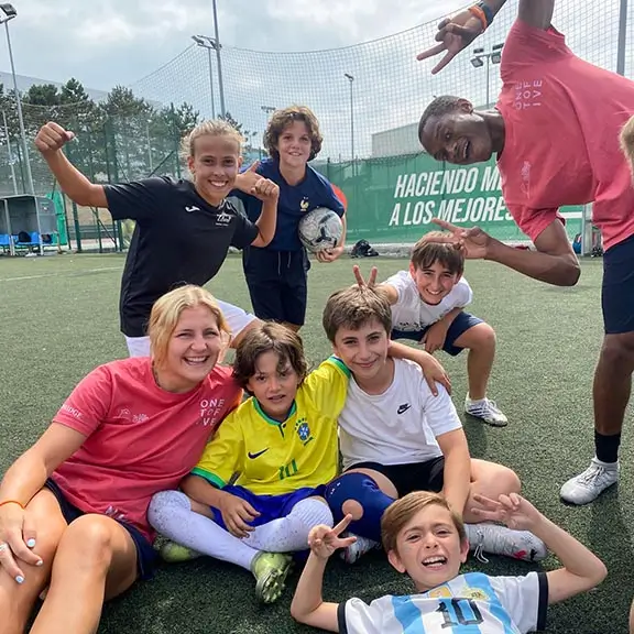 Partecipanti dell'attività di calcio che posano con i loro coach internazionali dopo l'allenamento.