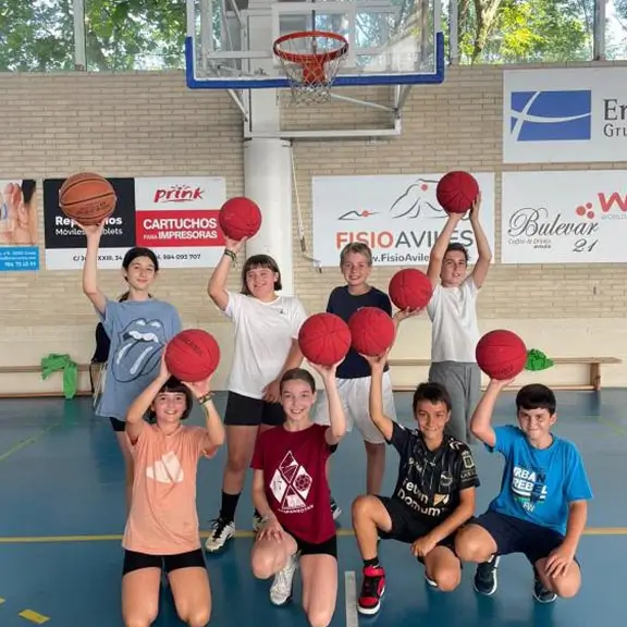 Partecipanti di basket che posano con i loro palloni al campo in inglese in Spagna