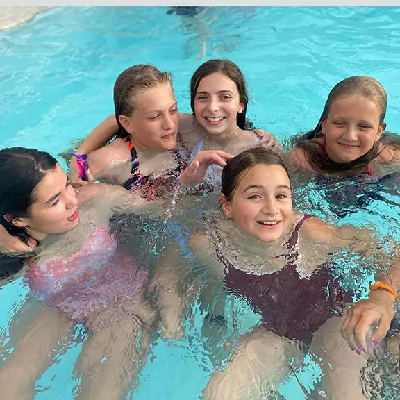 Gruppo di ragazze che nuotano nella piscina al campo estivo in Spagna.