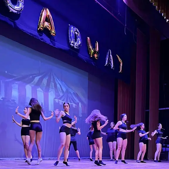 Gruppo di ragazze che eseguono una danza davanti ai loro amici al campo estivo